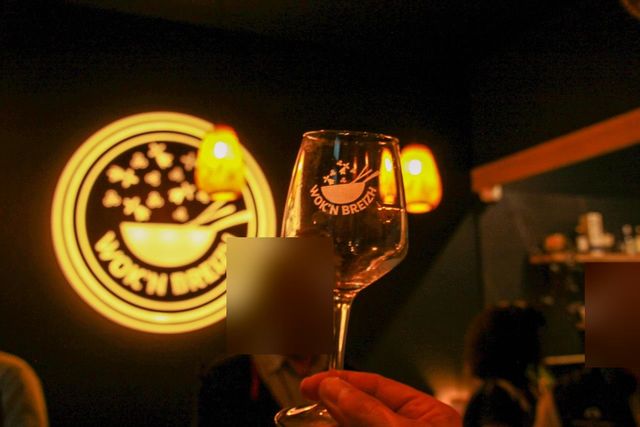 A glass etched with the Wok'n Breizh logo raised in front of the restaurant's illuminated sign